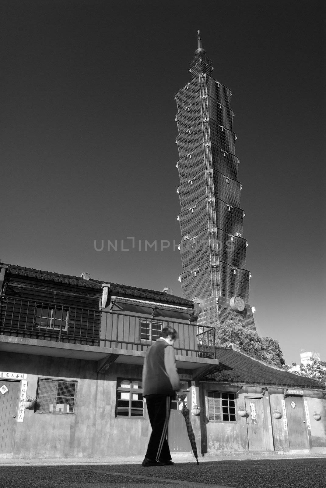 Taipei 101 was a famous landmark in world. In front of this skyscraper was an old community. Another renewal scenery in morden city. In this picture, did aged woman walk and not stop mean the history not go back ?