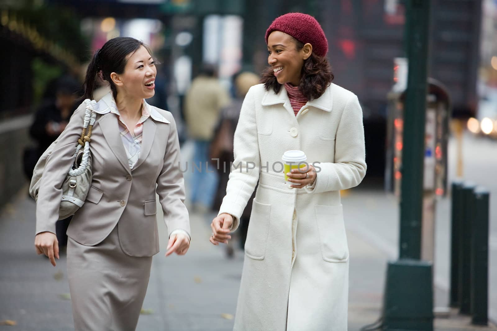 Two business women having a conversation while walking in the big city. 