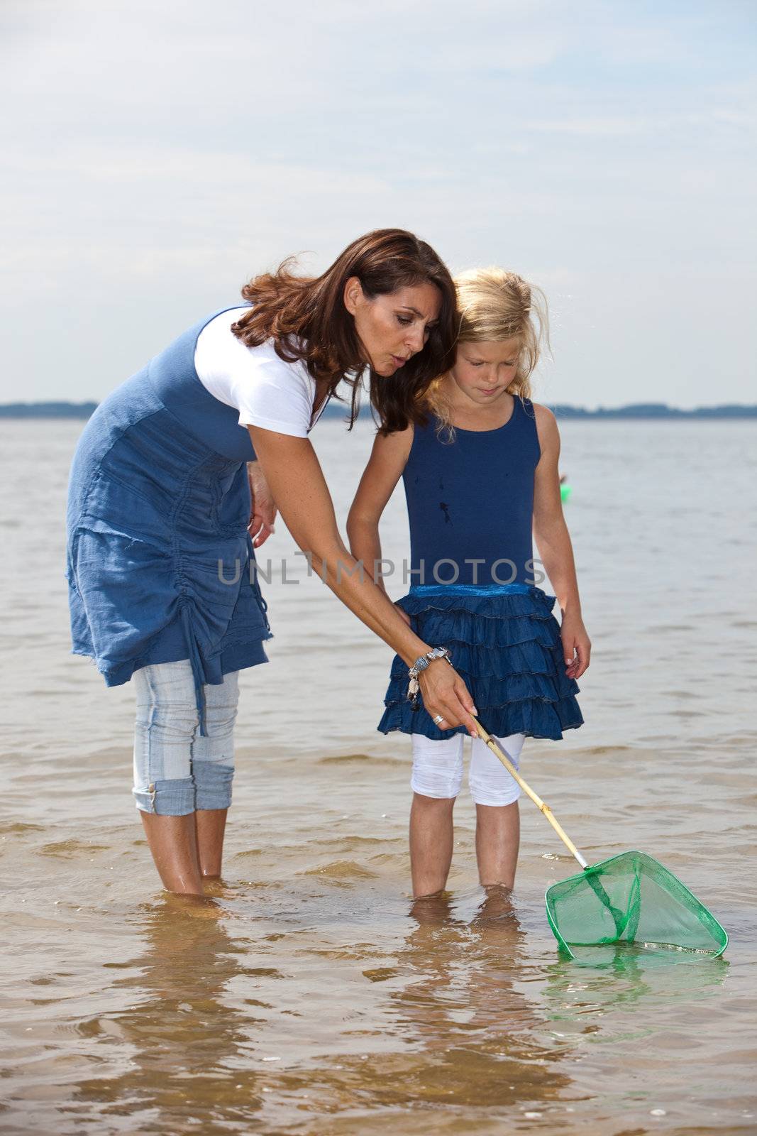 Mother and young child looking for shrimps by the waterside