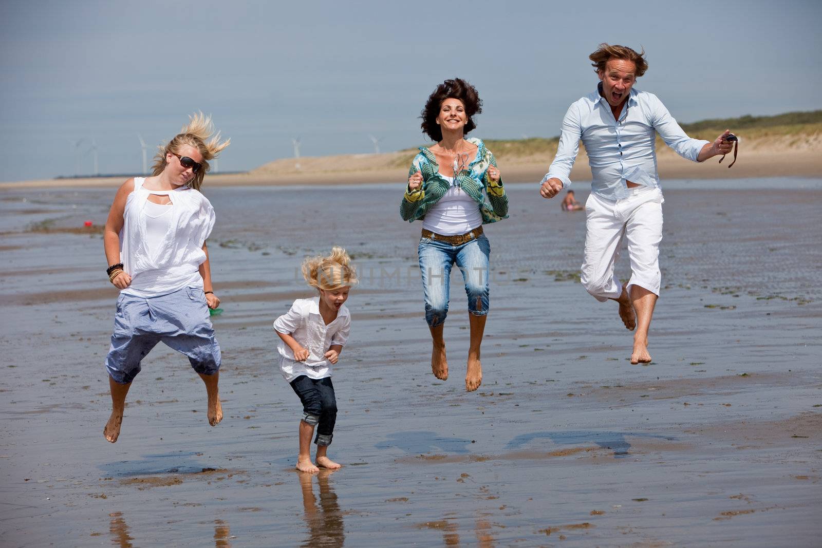 Happy young family at the beach jumping