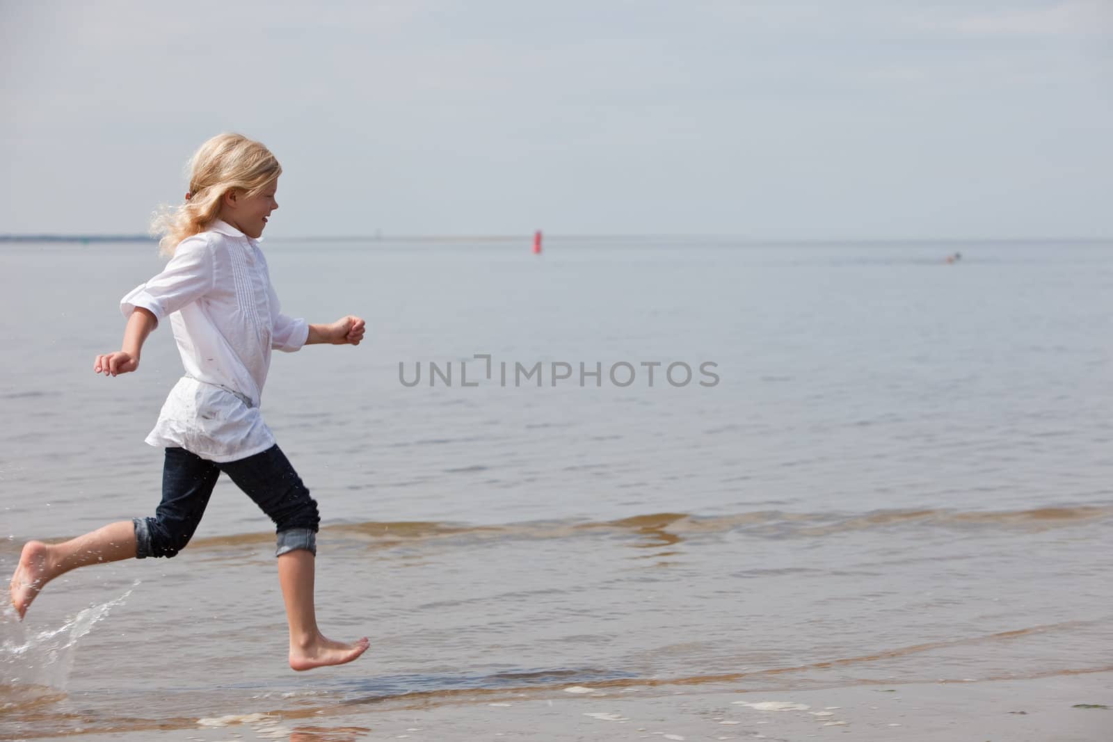 Young child running along the beach at the waterline