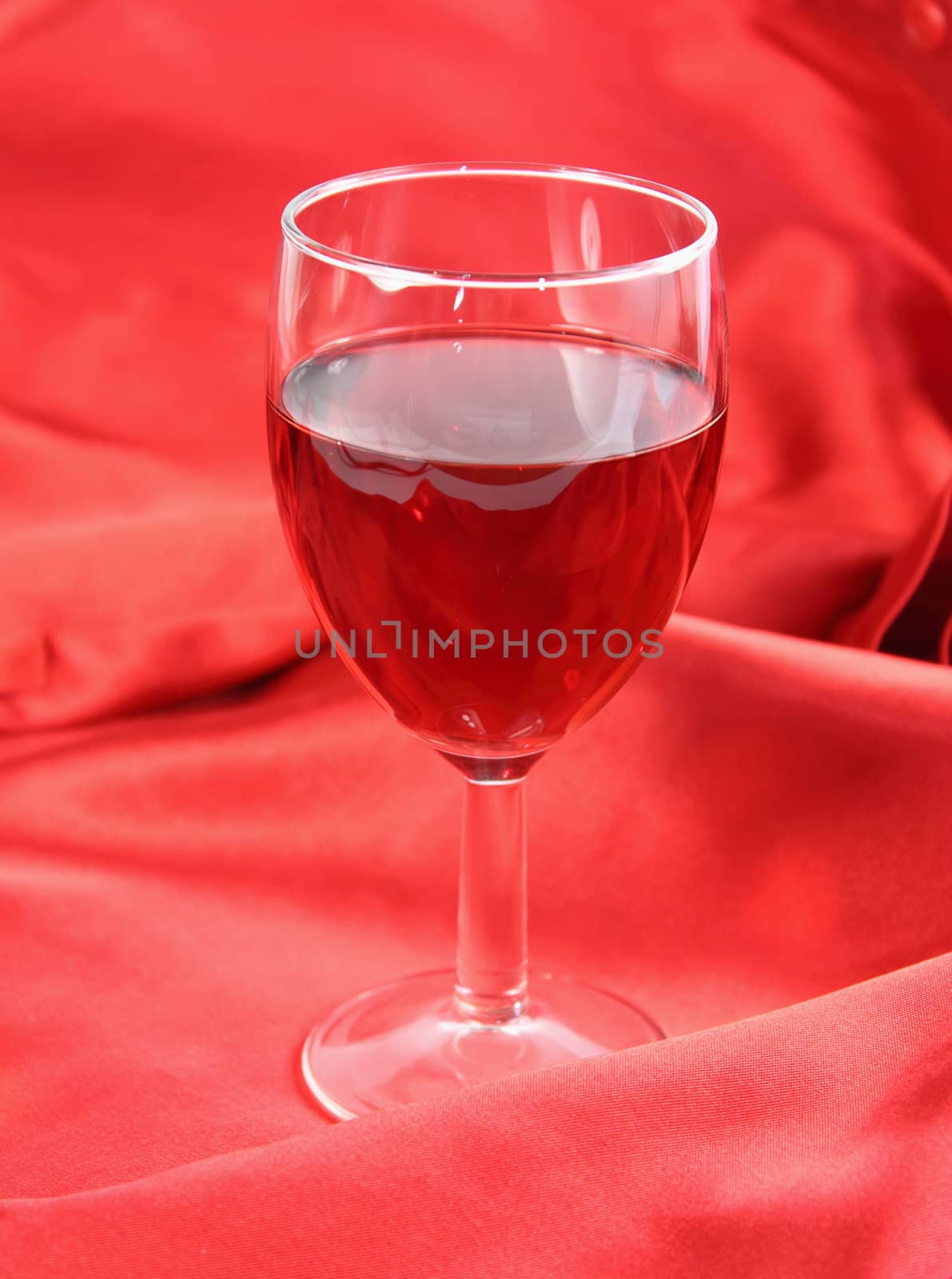 Glass of red wine on red satin background