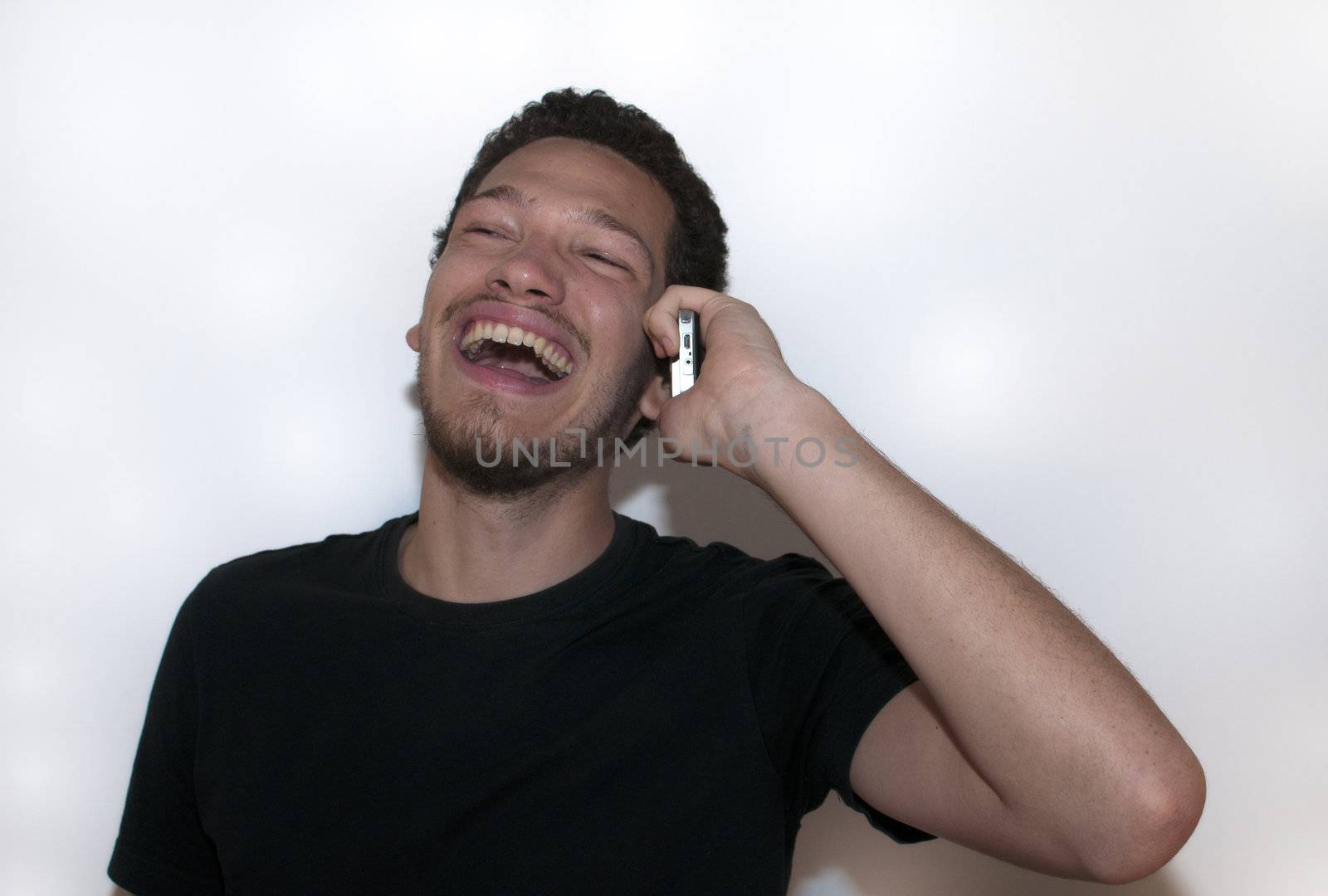Casual young man laughing on the phone on isolated background