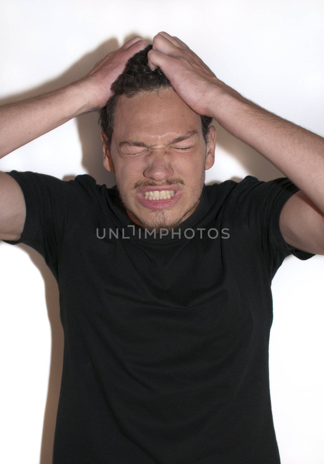 Causal young man pulling his hair out of frustration on isolated background 