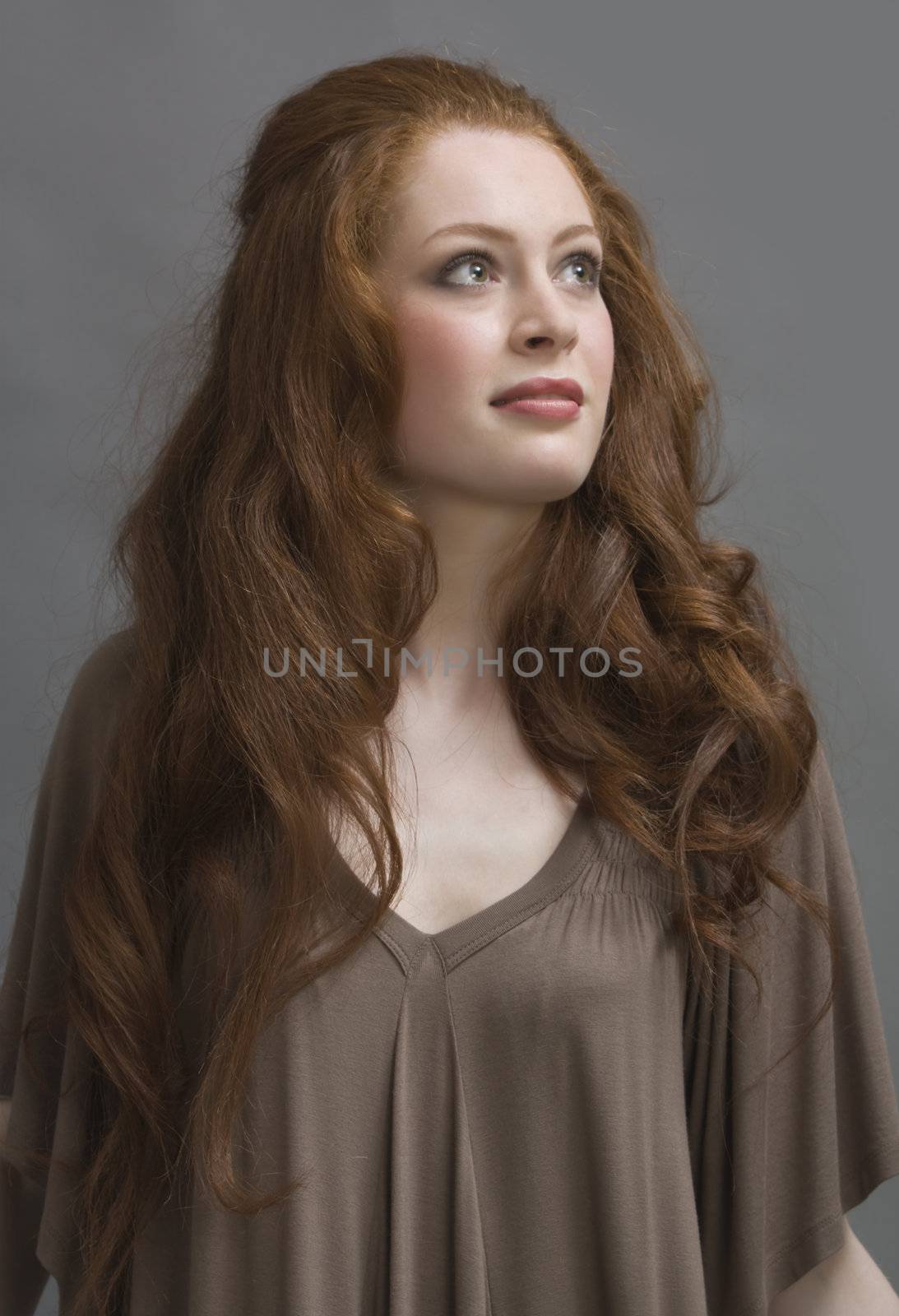 beautiful redhead girl in studio on a gray background