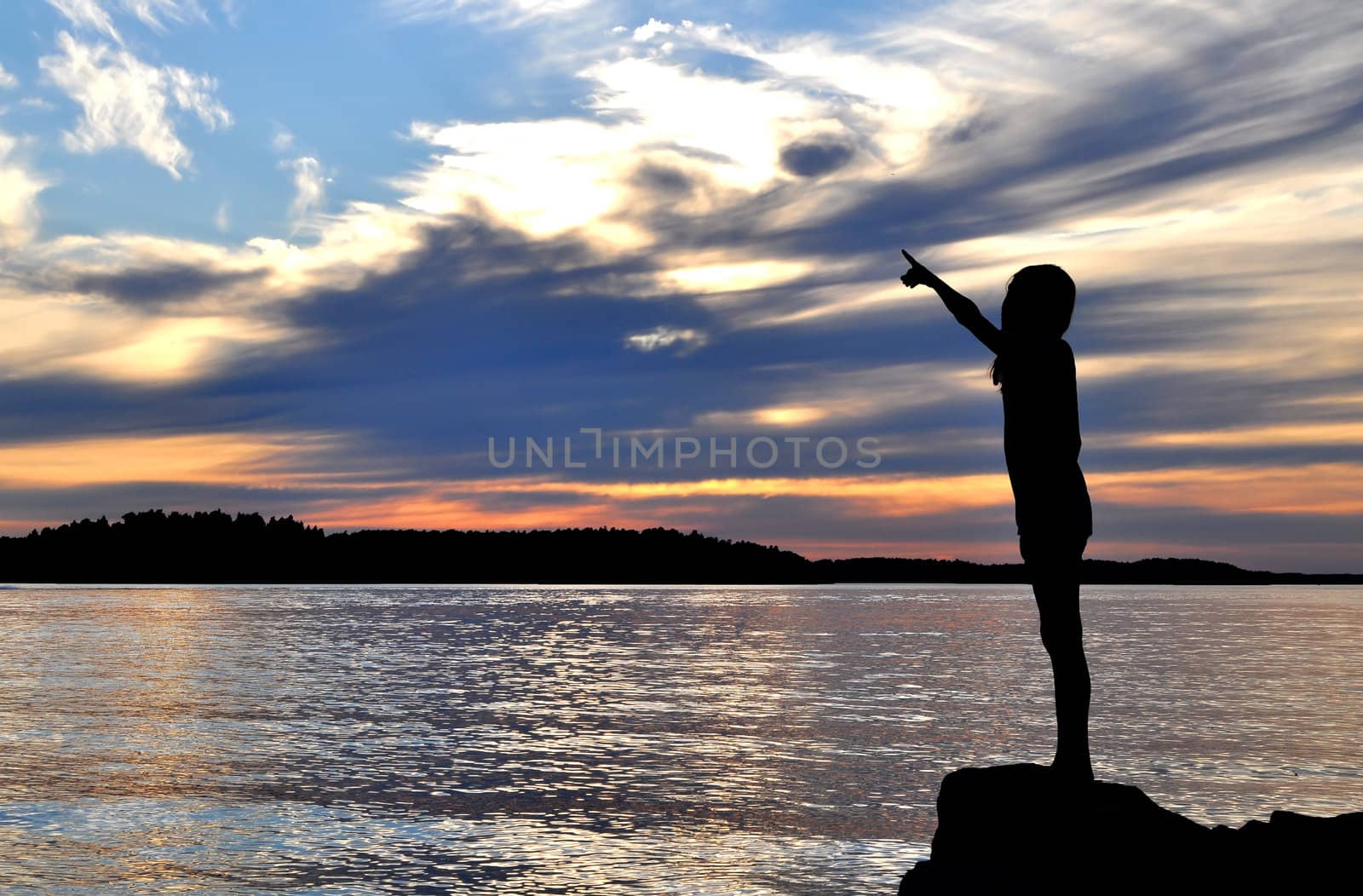 The silhouette of a young girl pointing to sky in the archipelago of Stockholm.