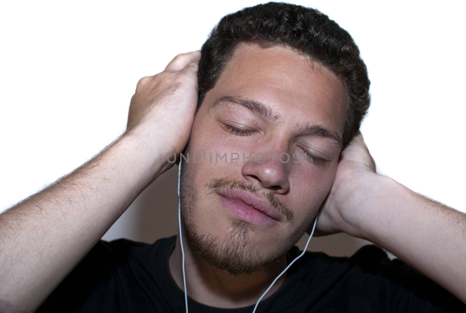 Young casual man listneing to music  through head phones on isolated background 