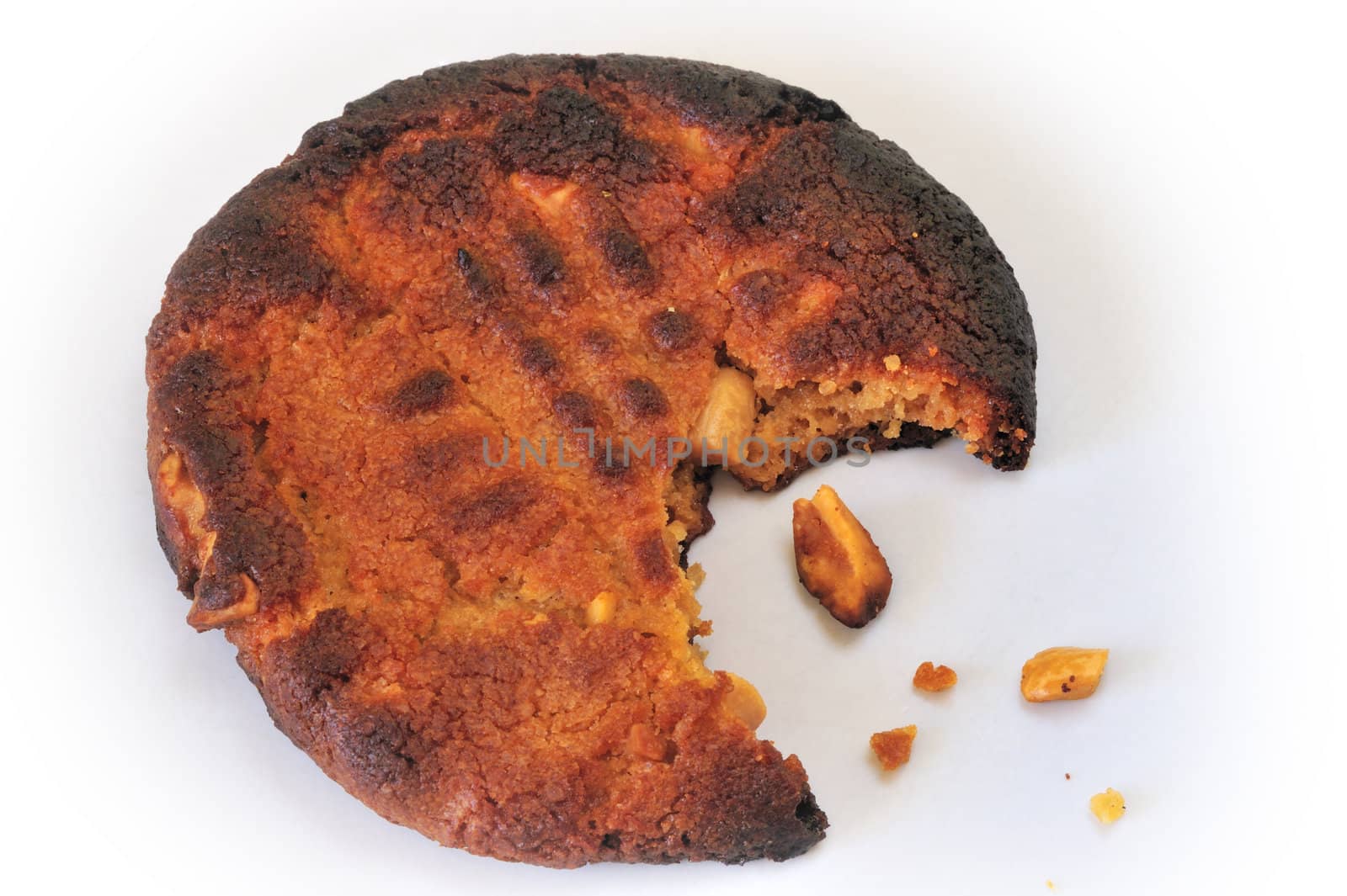 A burned, half-eaten biscuit, with a few crumbs, on a white background.