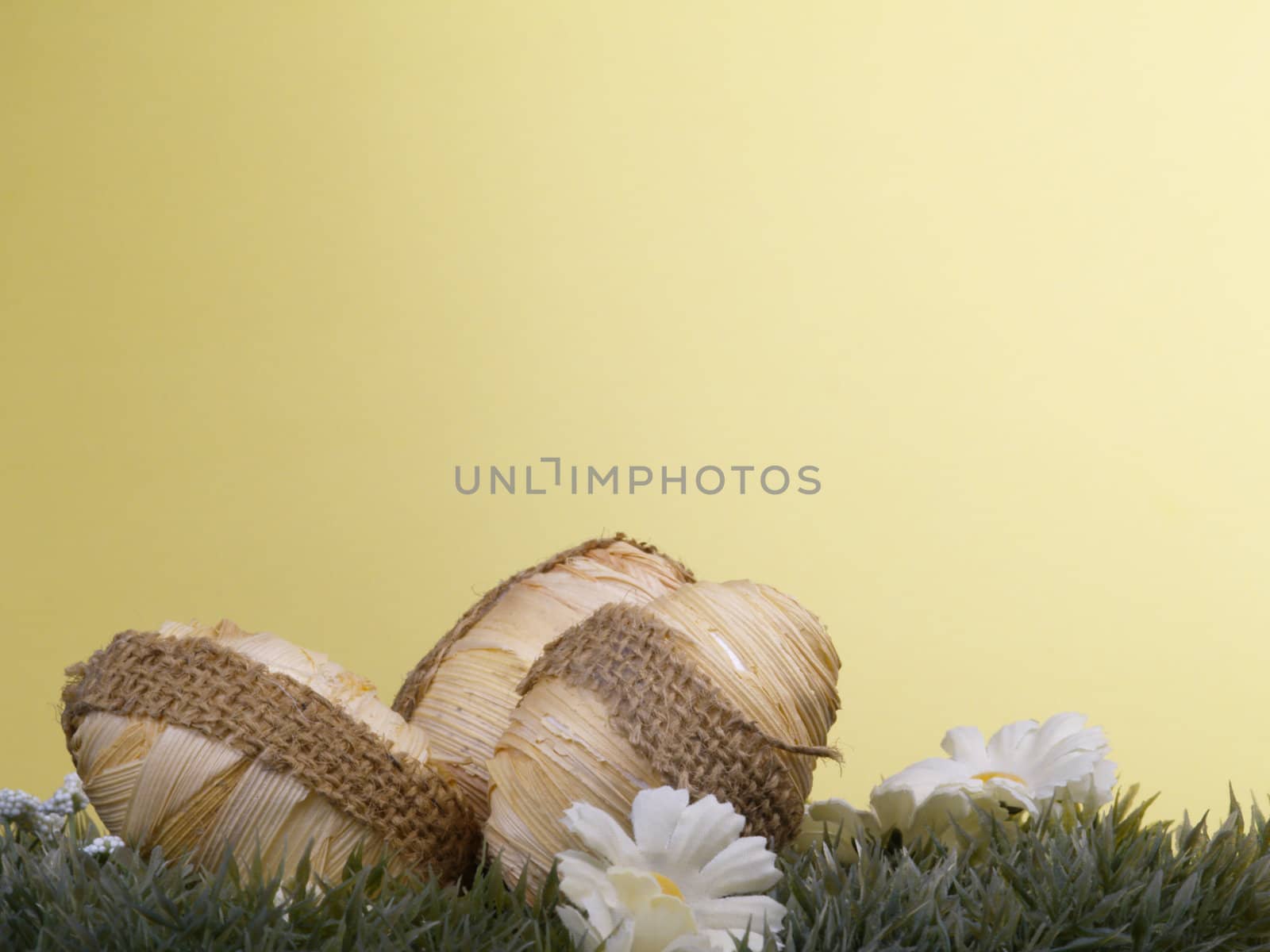 wrapped design on easter egg, artificial grass and blossoms, yellow background