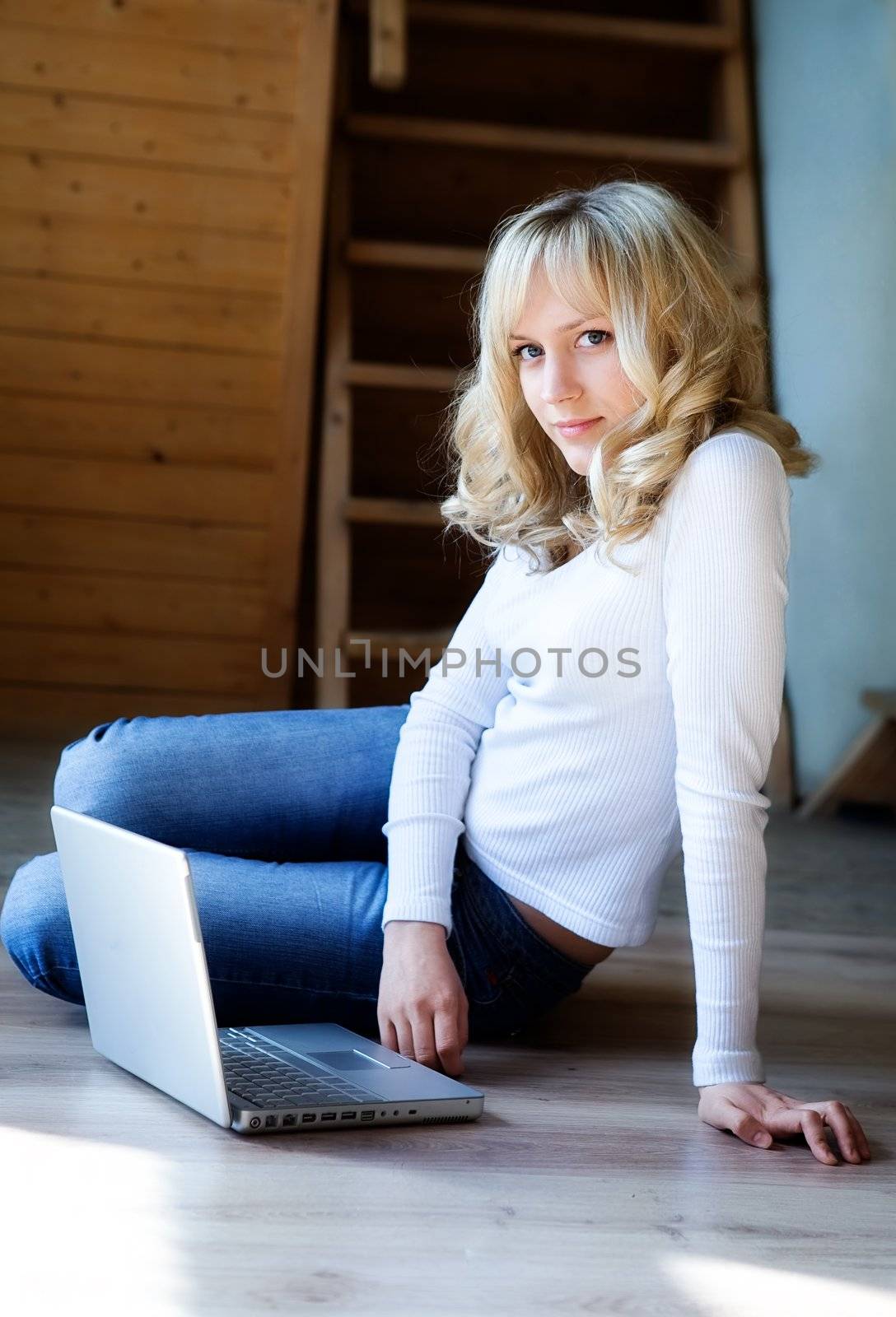 Fair-haired girl in jeans and a white blouse  with the computer