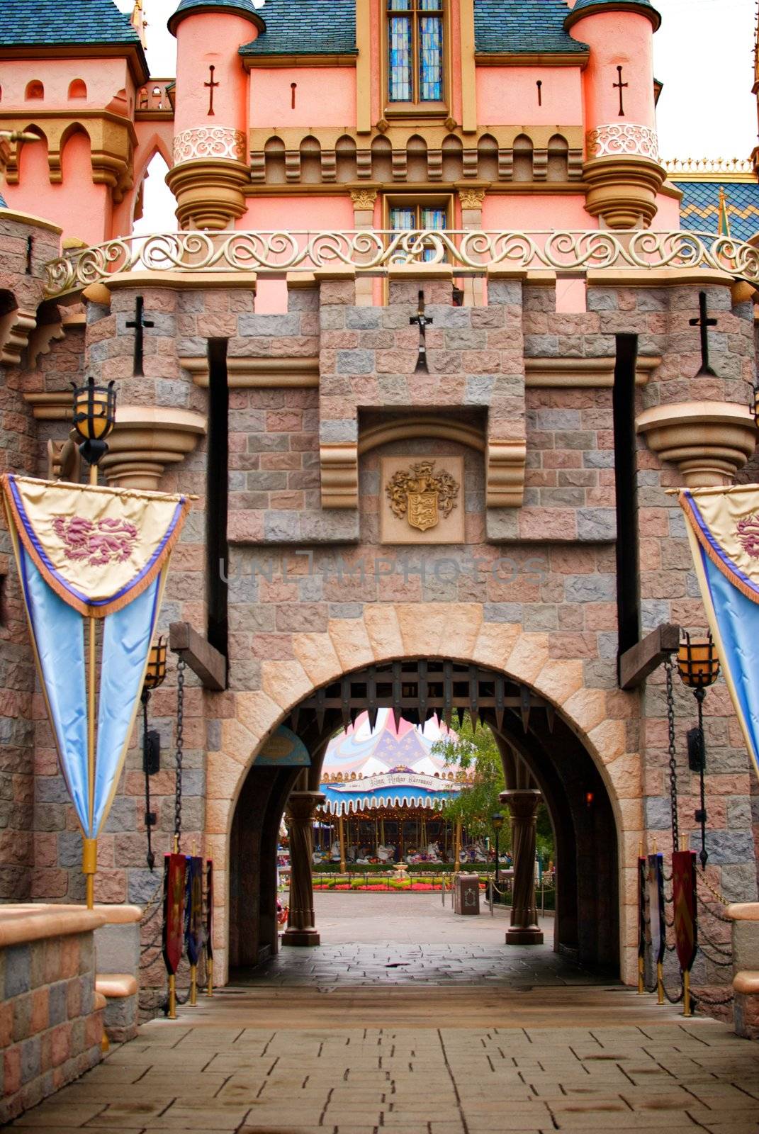 Looking through a fantasy castle's draw bridge entrance to see a carousel in the distance