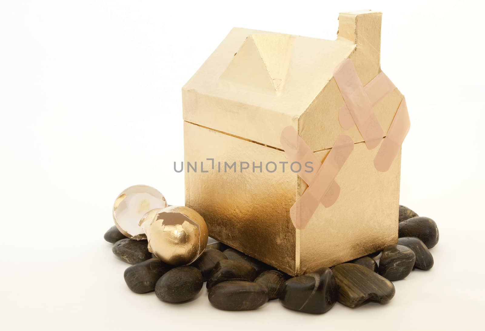Golden house and broken nest eggs reflect the dire situation of real estate investments on the rocks resulting in broken nest eggs, retirements in need of first aid, and destroyed dreams