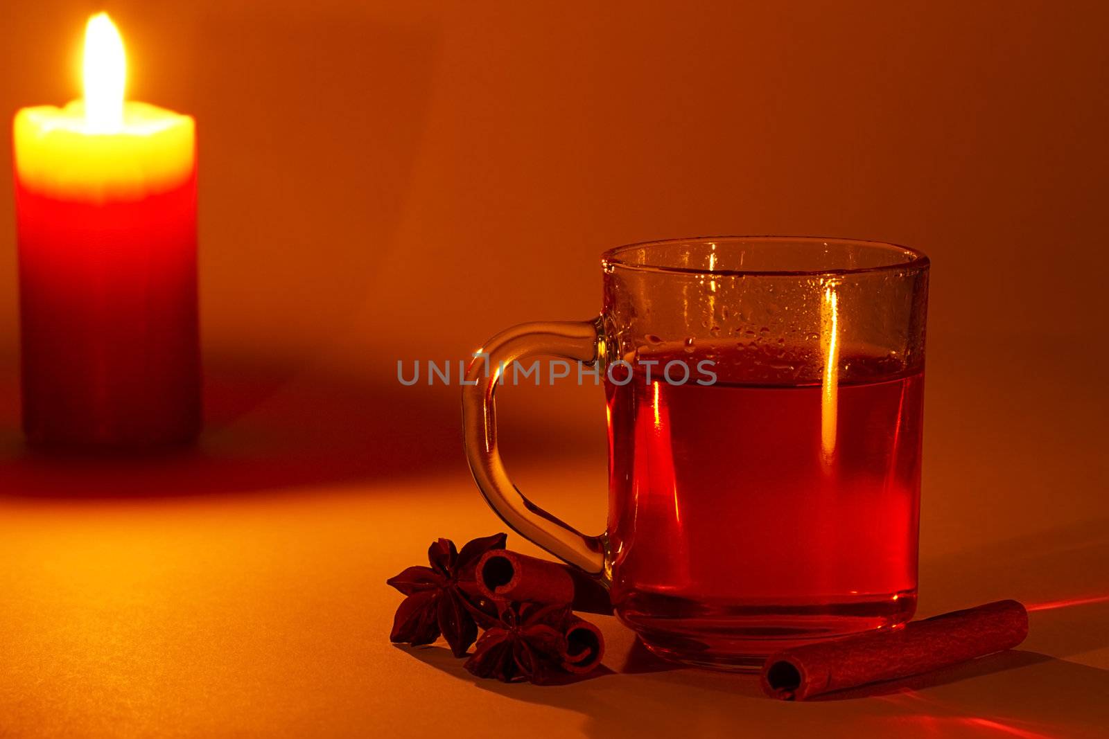red tea in a glass, cinnamon sticks and star anise at candle light