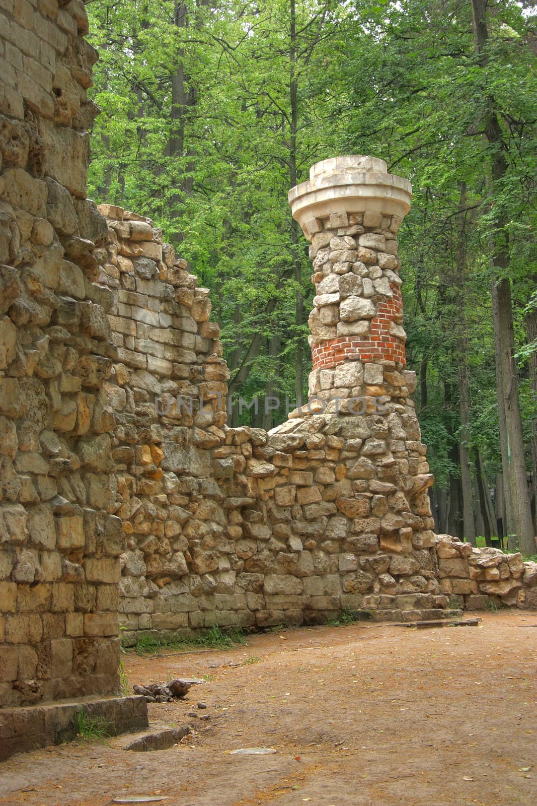 Old stone wall with tower in summer park