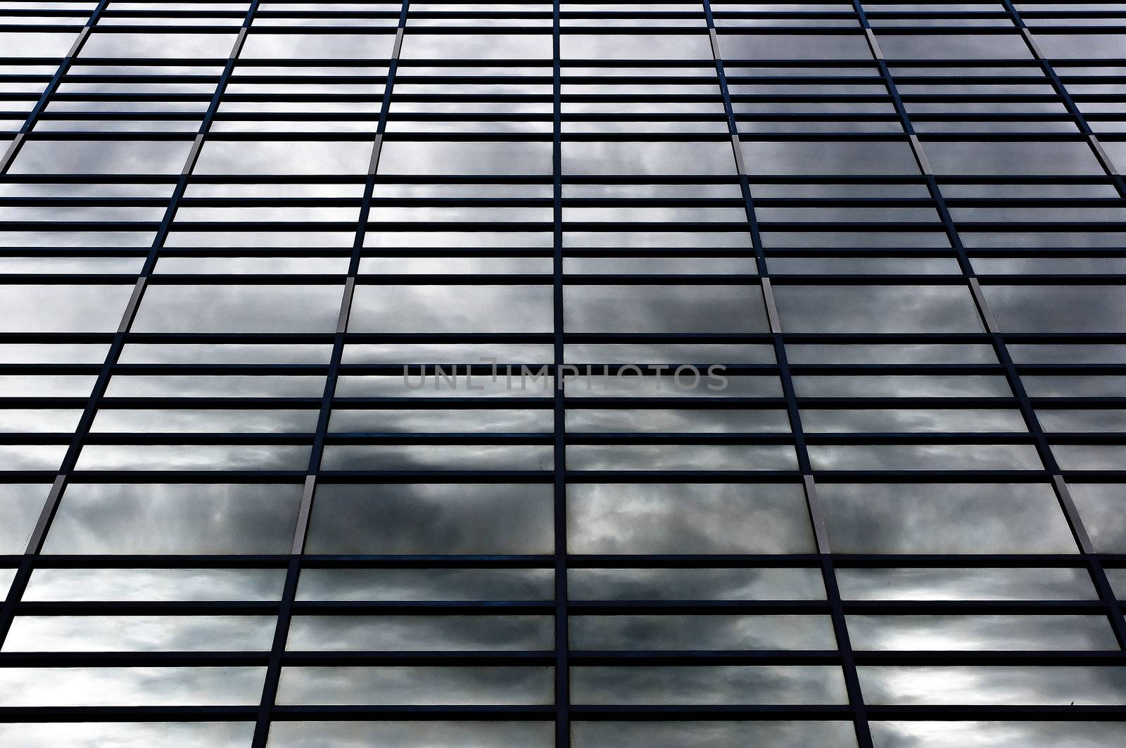 A selective shot of rows of windows in a grid pattern reflecting stormy skies.