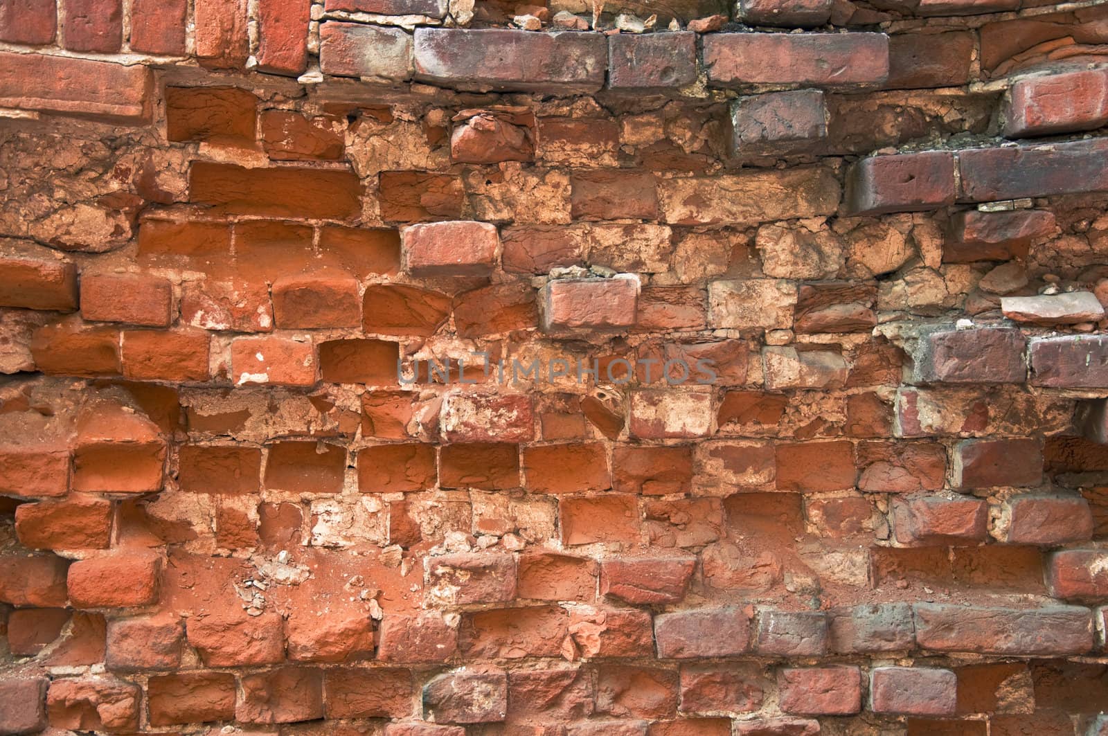 Old dilapidated brick wall. Uneven rows of masonry and pelted with bricks.