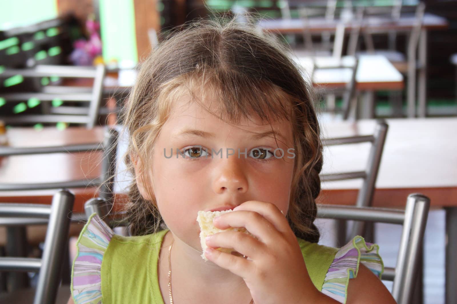 preschool-age girl eats bread in the dining room