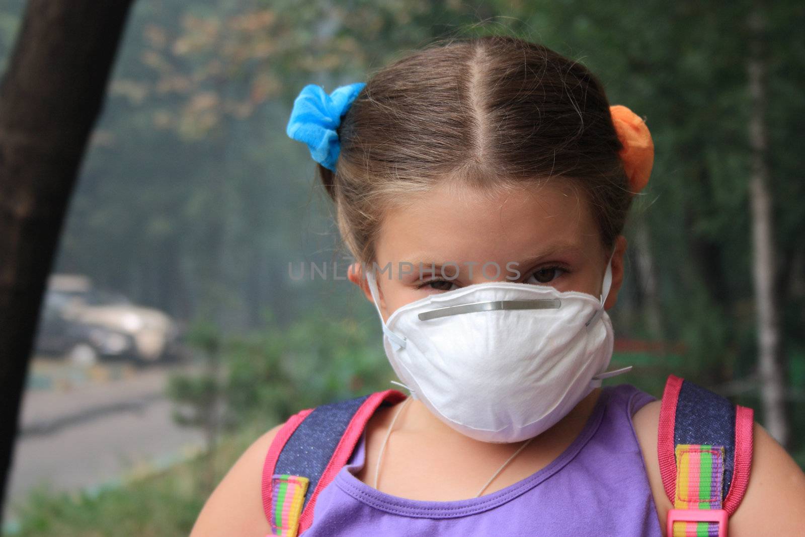 Preschool girl in a breathing mask in a house court yard