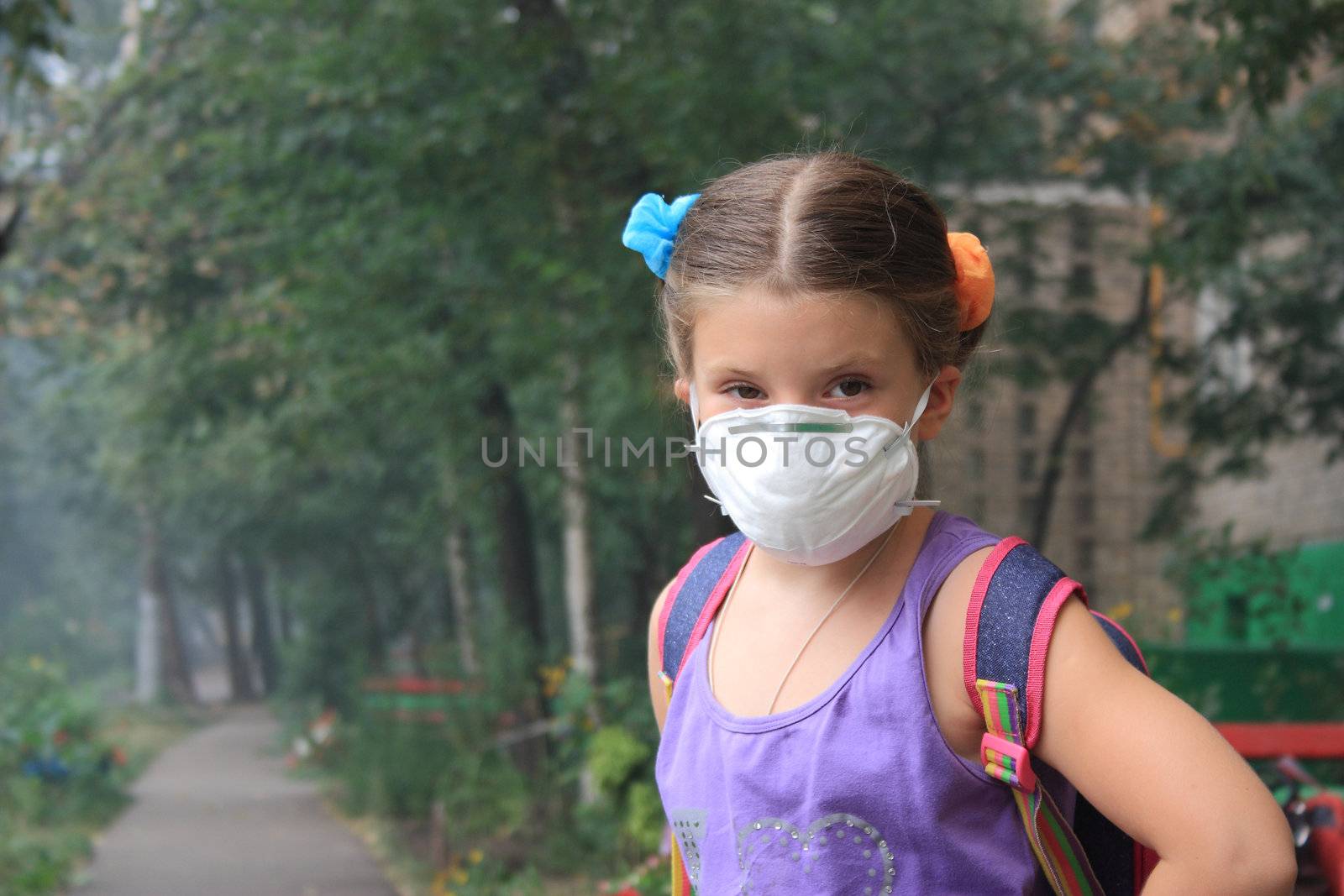 girl in a respirator in a smoke-filled backyard