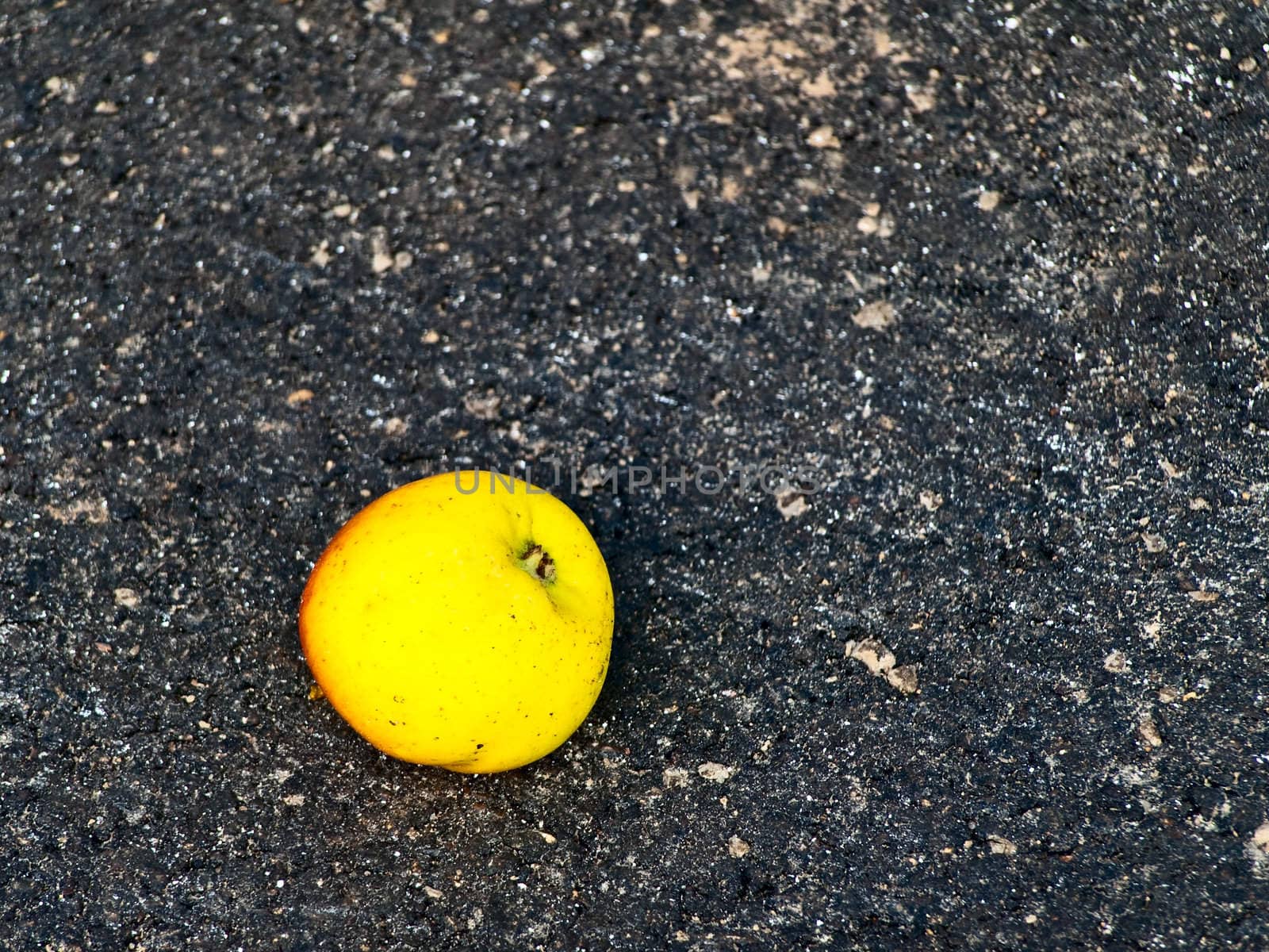 green apple at the black asphalt