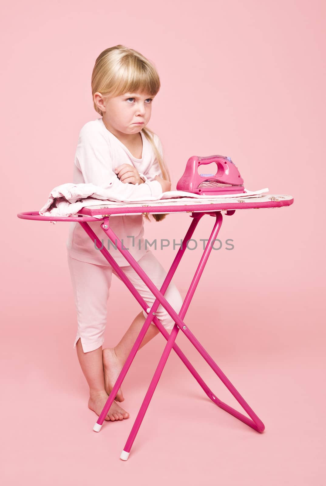 Angry girl with an iron on pink background