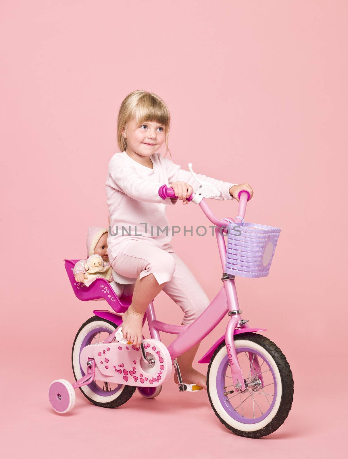 Young girl on her bike towards pink background