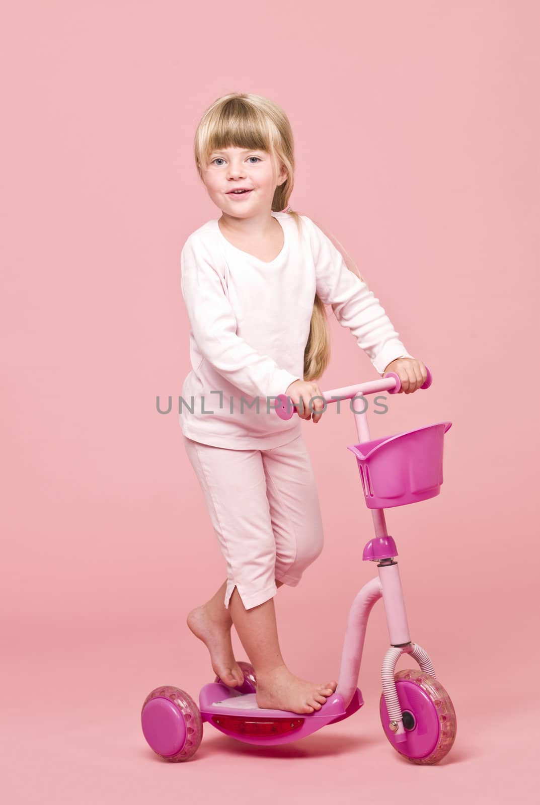 Young girl with a Scooter towards pink background