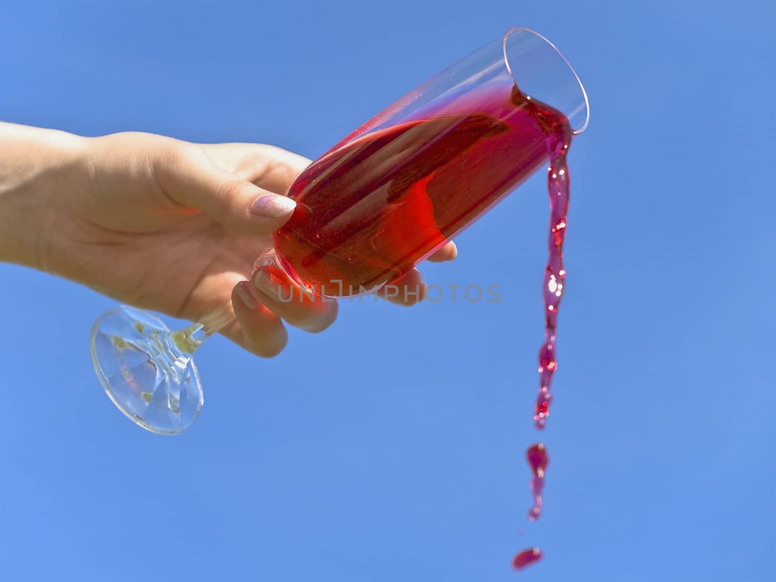 woman hand pour red drink from wineglass