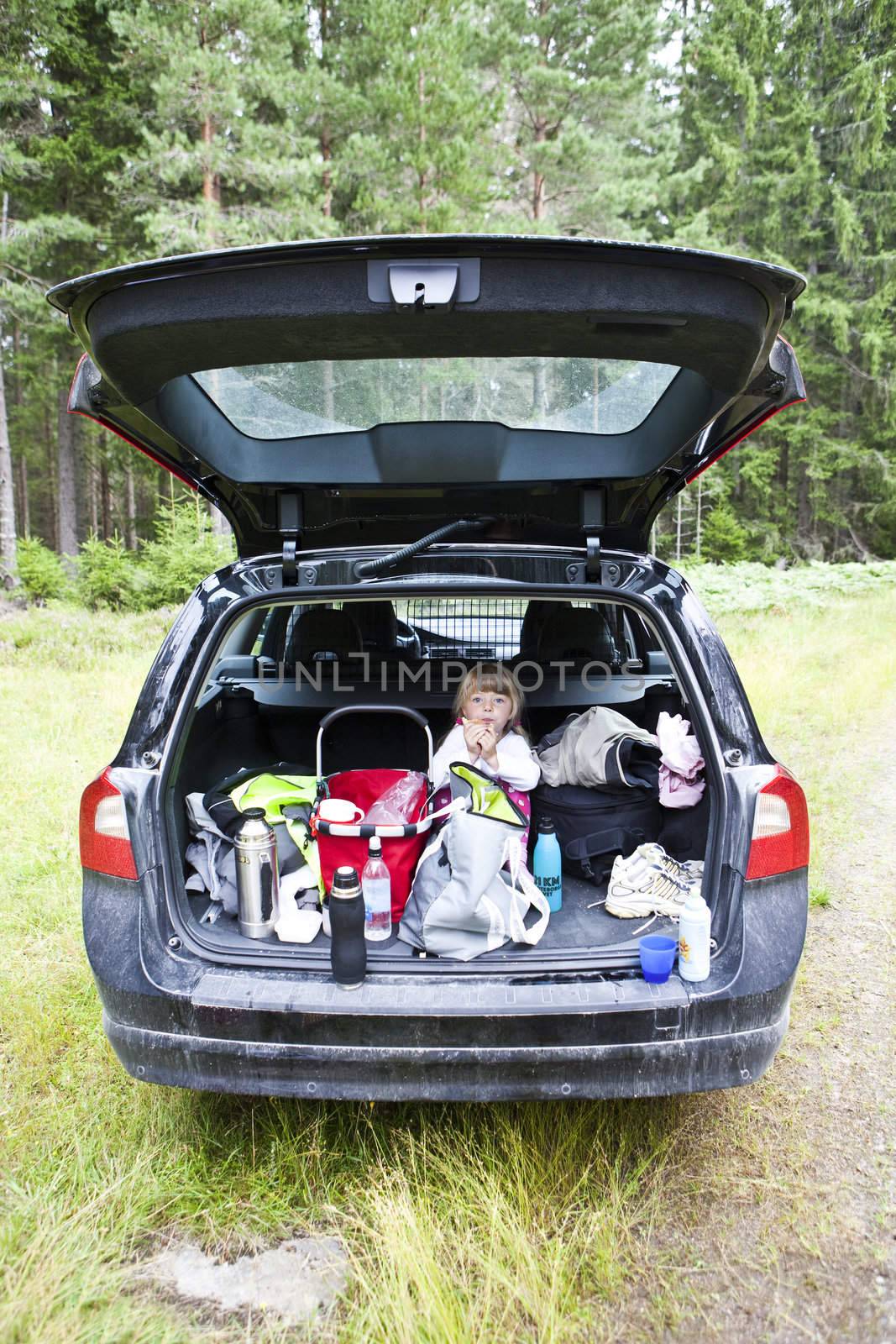 Young girl sit in the back of a car eating