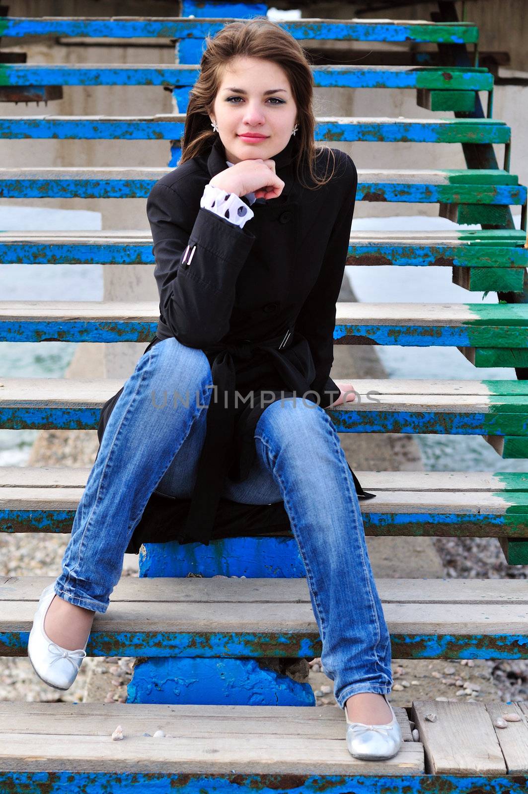 sweet teen girl  sitting on the stairs on the beach