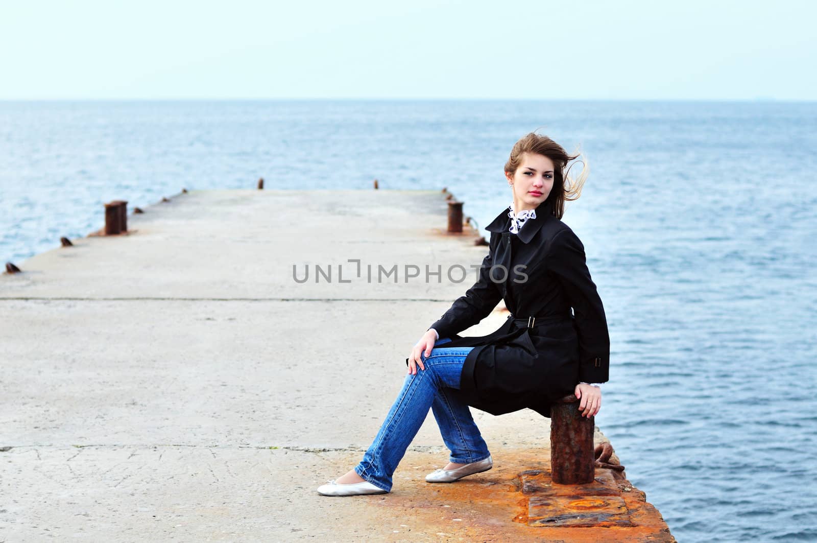 teen girl sitting on the dock in windy weather
