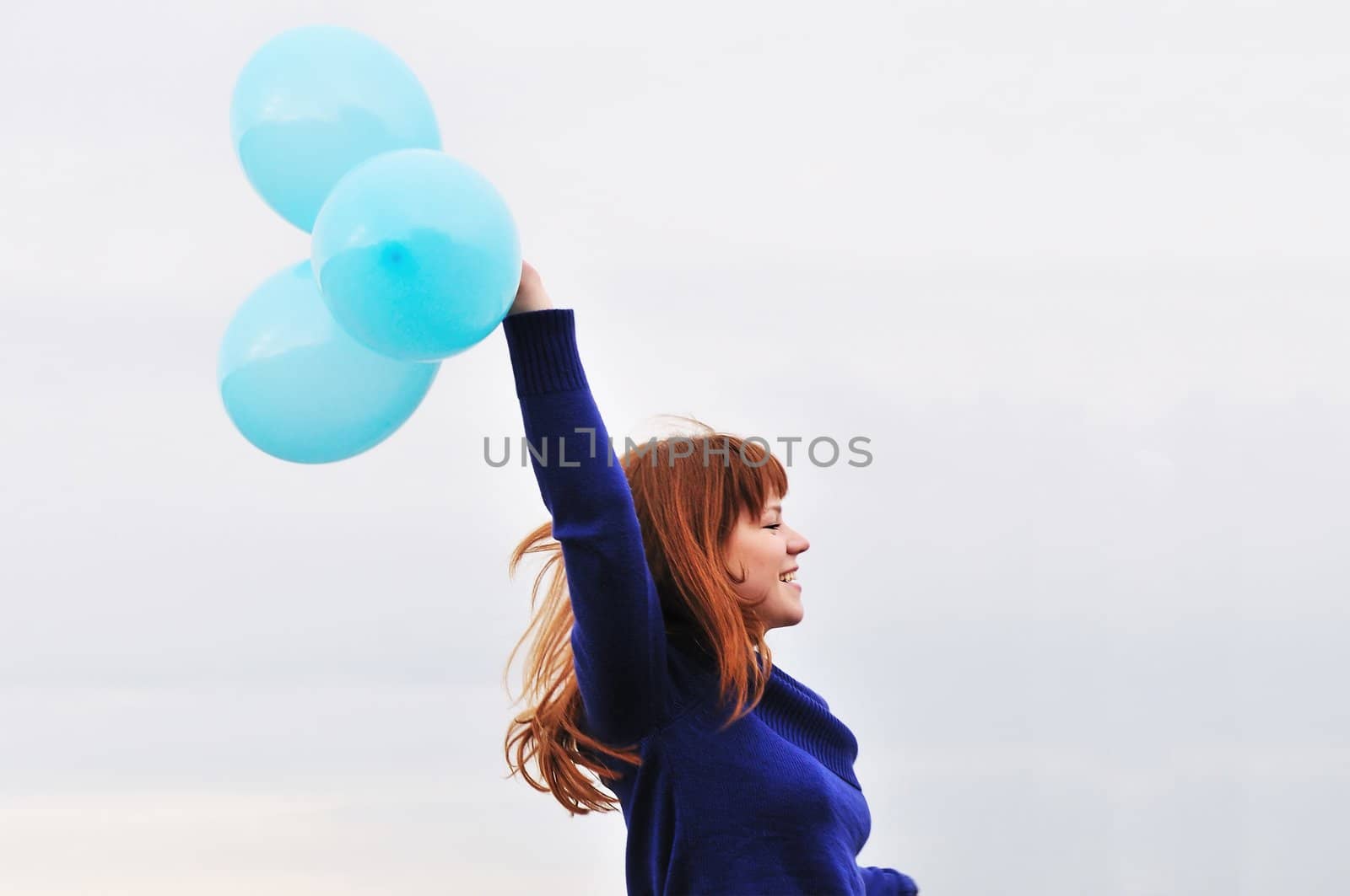 redheaded girl running with balloons over the sky