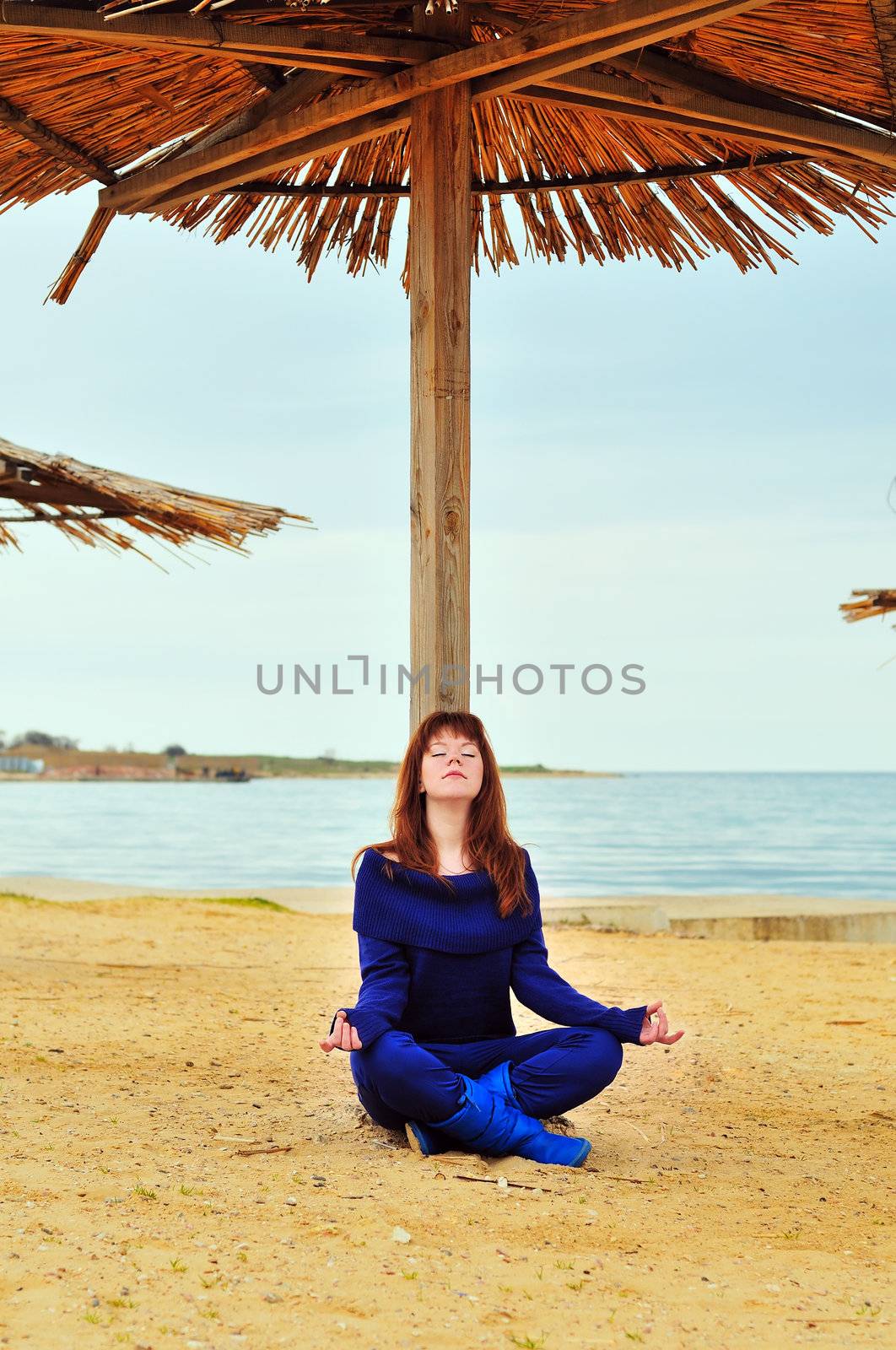 redheaded pretty girl meditating near the sea
