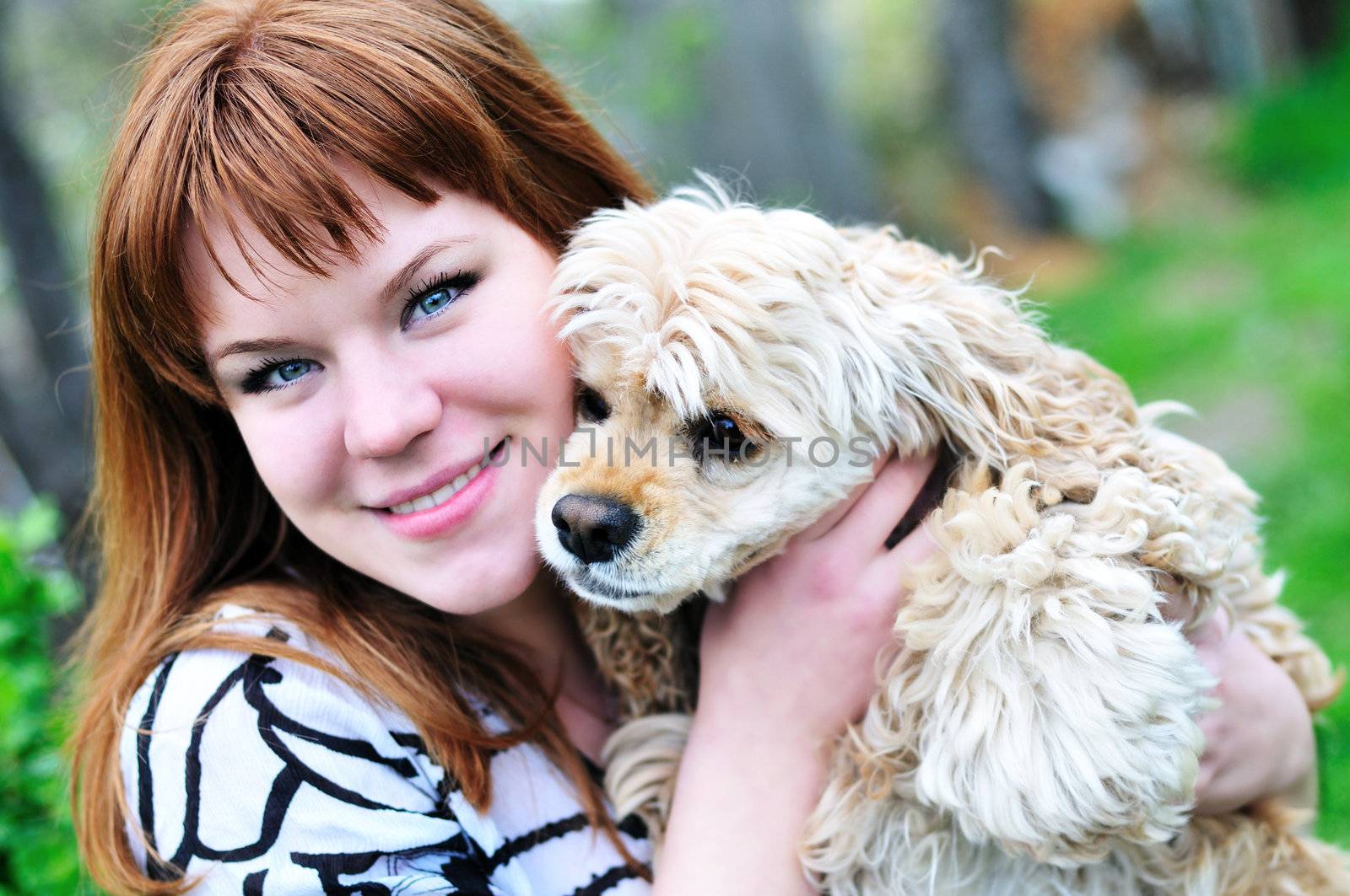 redheaded pretty girl hugging her dog on the meadow