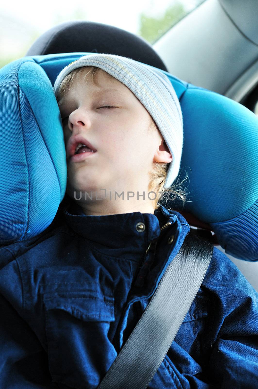 little boy sleeping  in car in own seat