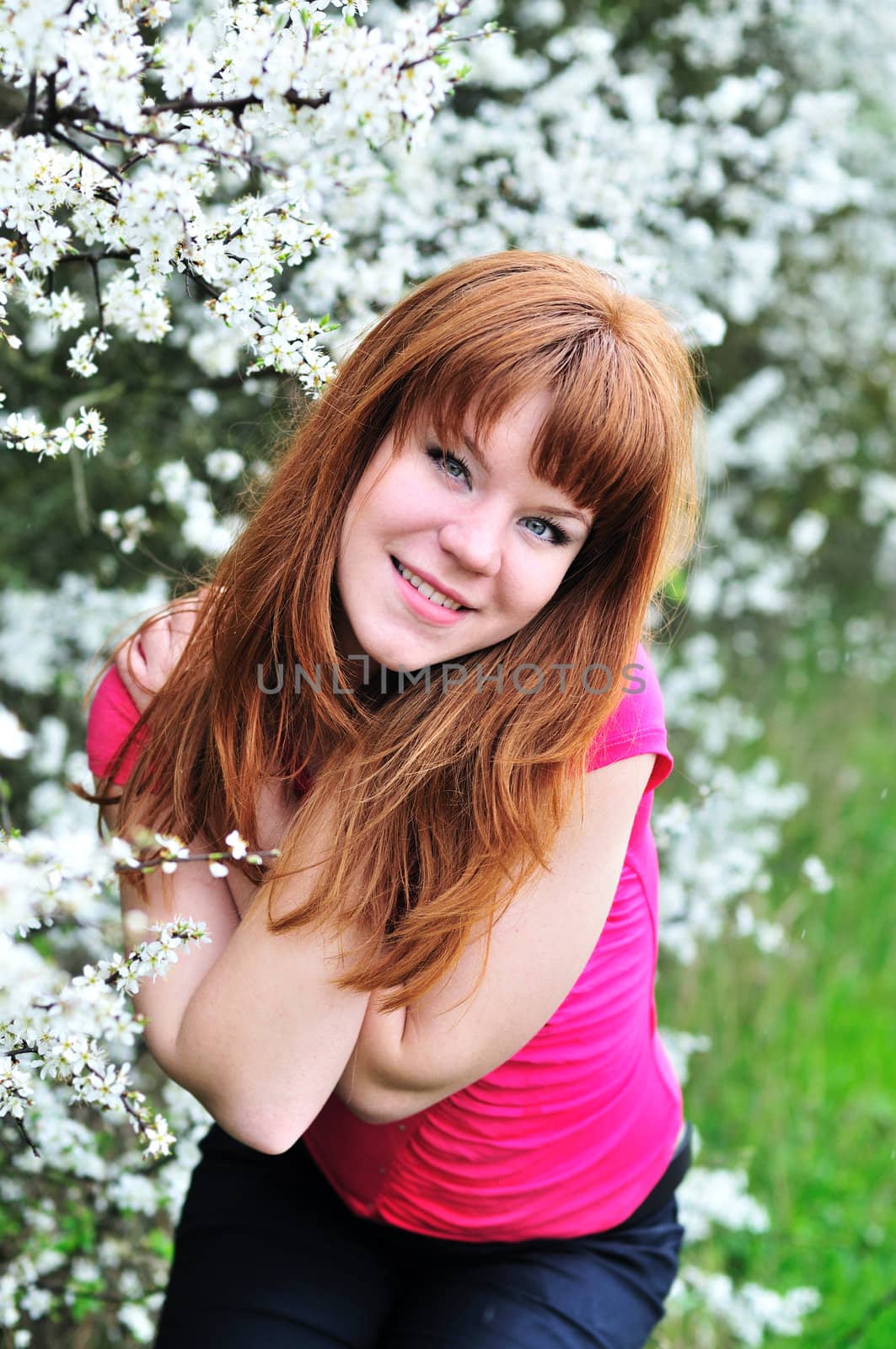 attractive redheaded girl having fun in blossom garden