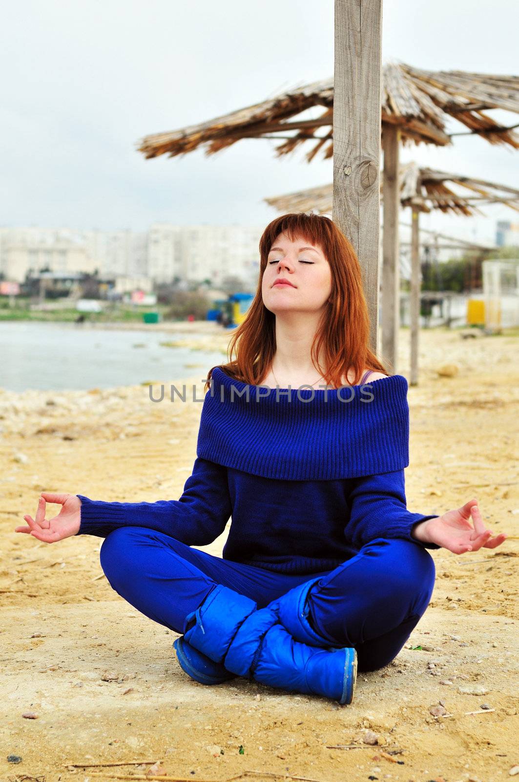 redheaded pretty girl meditating near the sea
