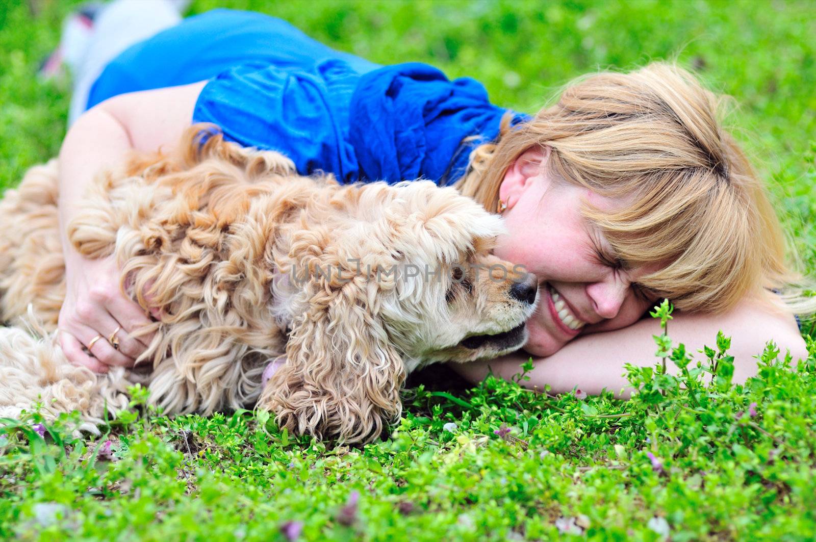 woman and her dog having fun in green grass