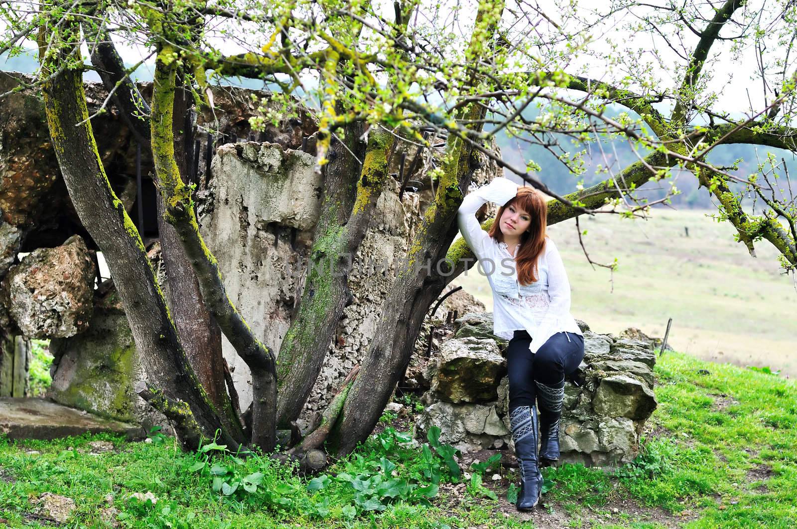  redheaded gorgeous girl sitting between tree and stone
