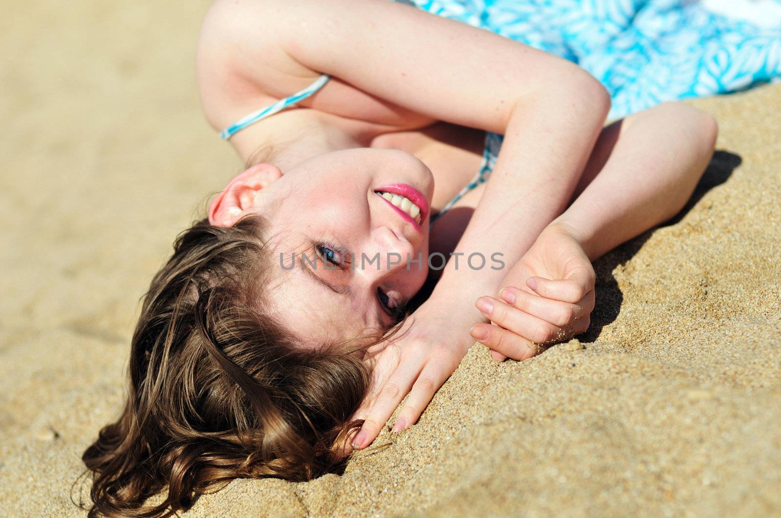 beautiful girl laying in sand in sunny day