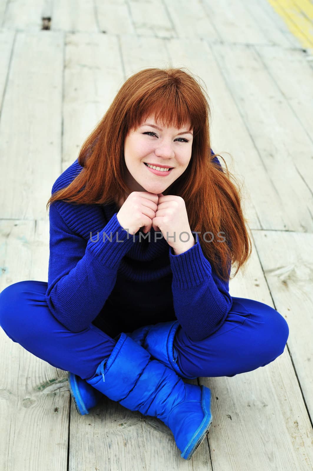 redheaded pretty  girl sitting on the pier 
