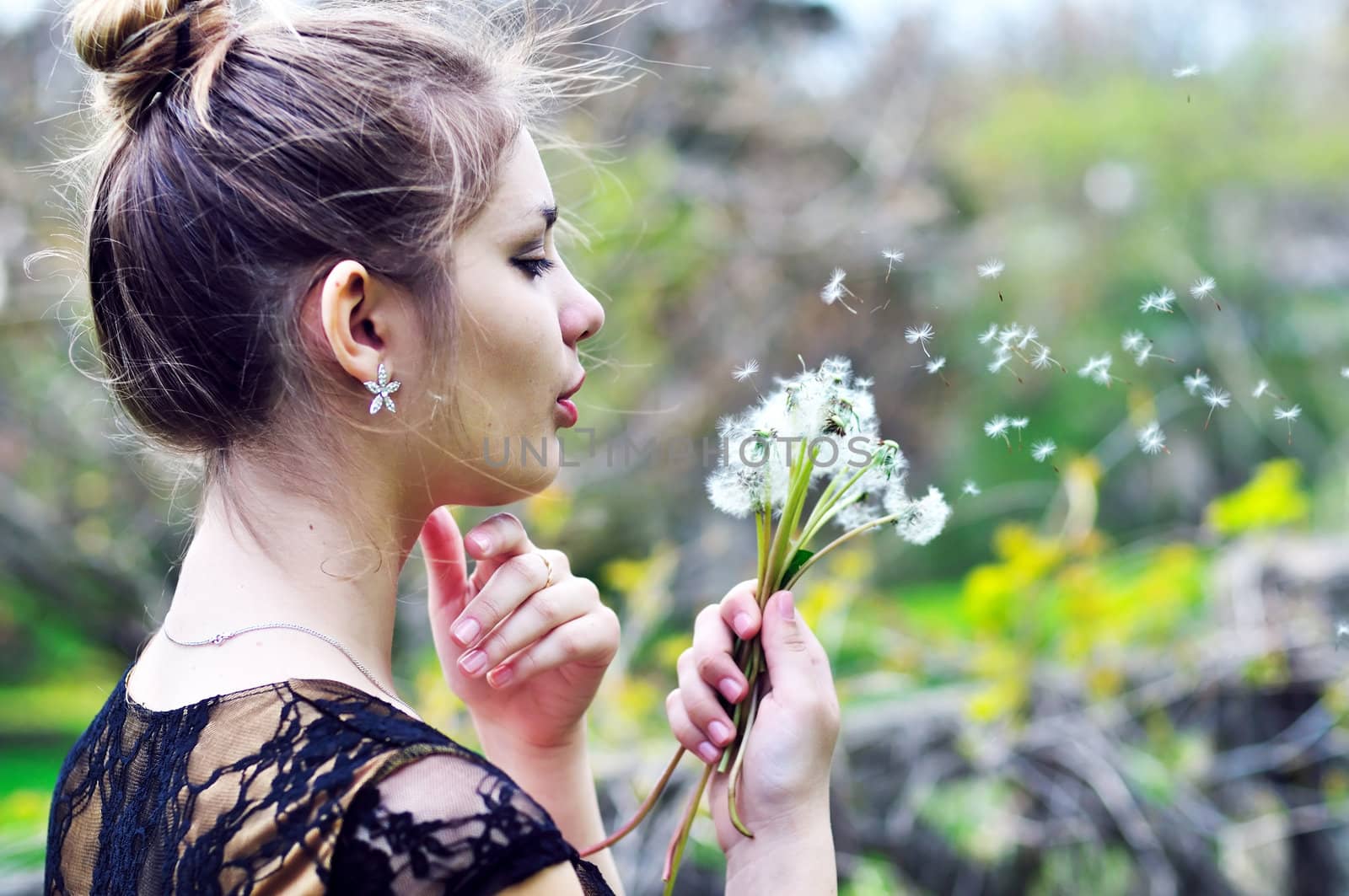 teen pretty girl blowing on many dandelions
