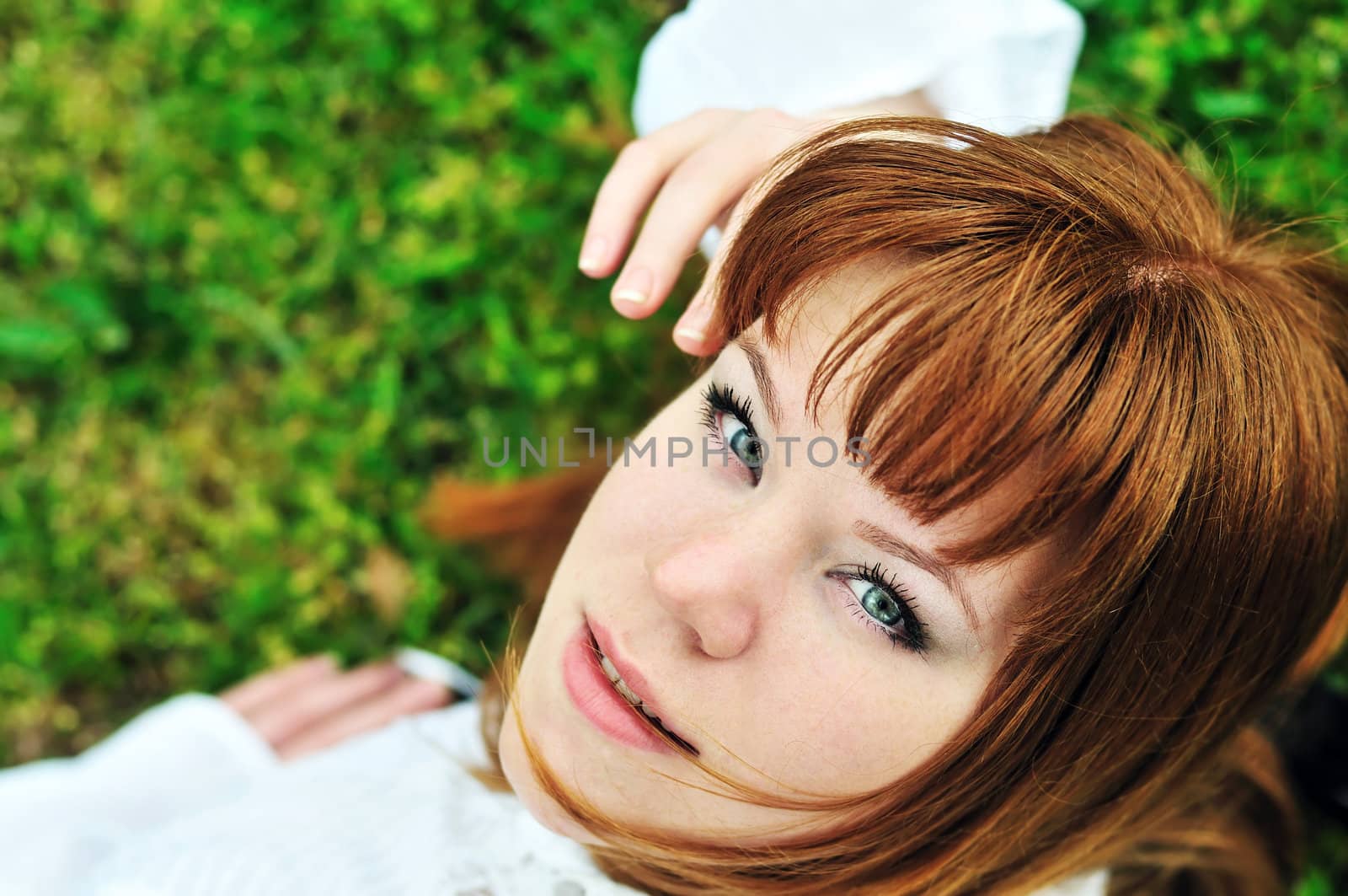 redheaded girl laying on the spring meadow

