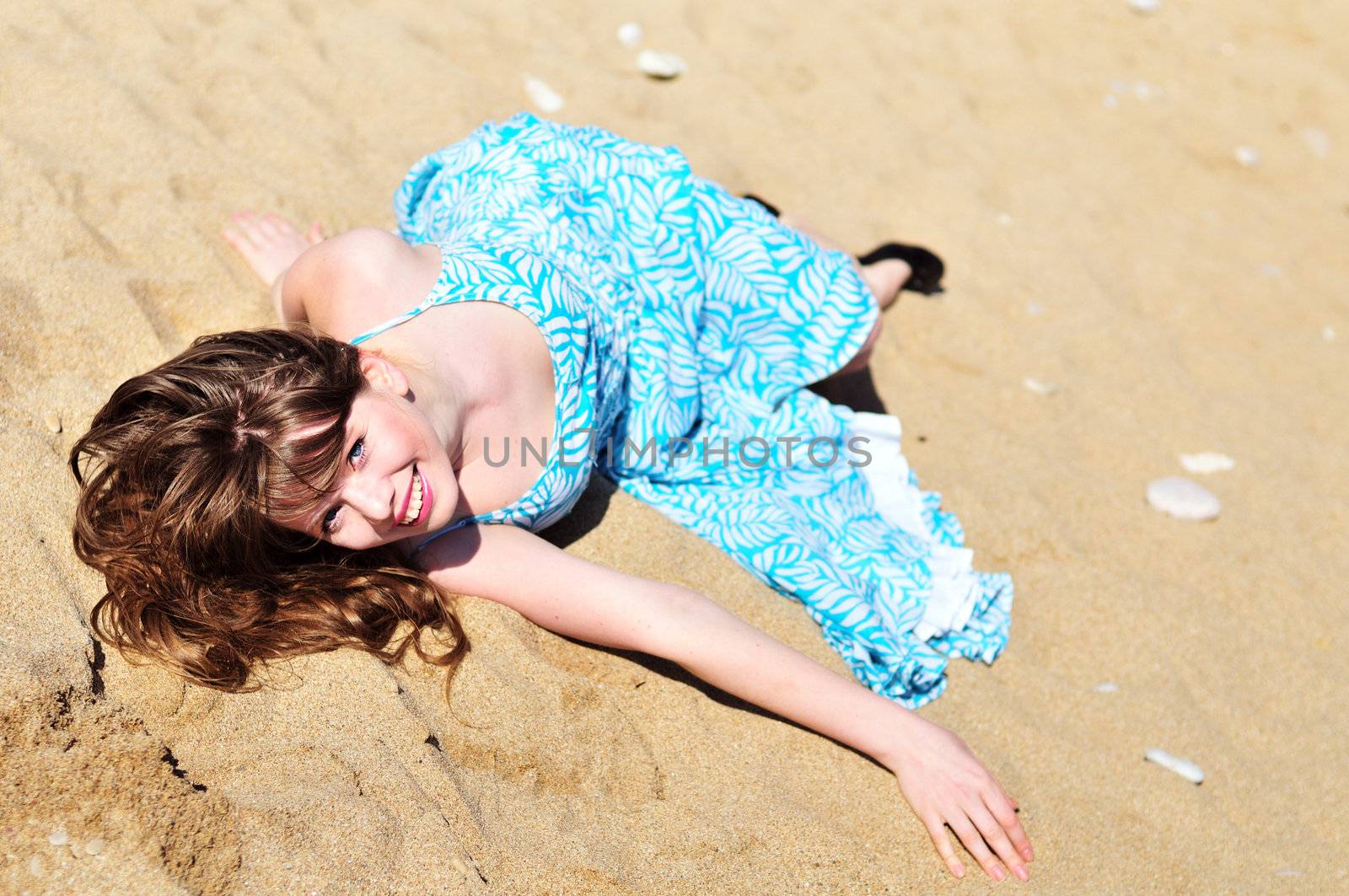 laughing pretty girl laying on the sand
