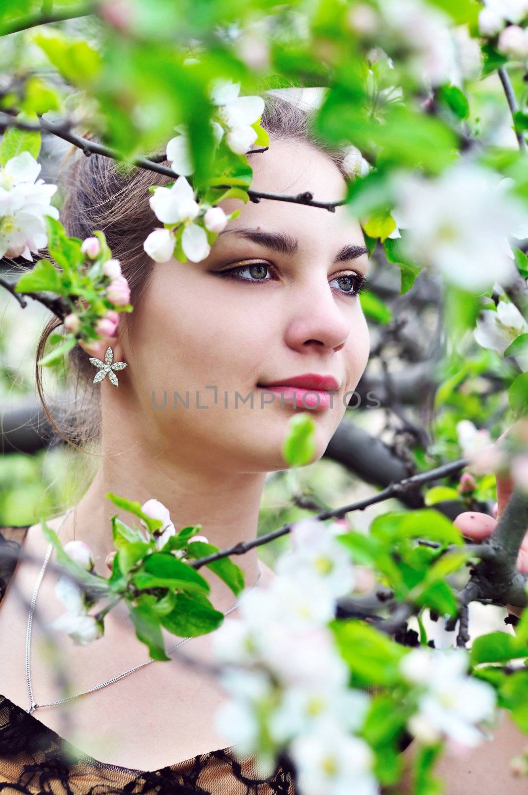 beautiful teen girl standing in the apple blossom