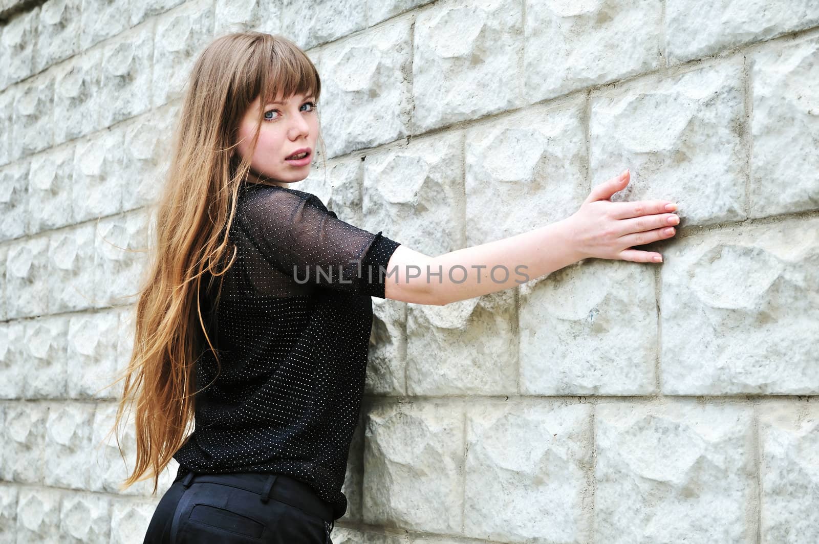 Blue-eyed long-haired girl leans on elbow wall 