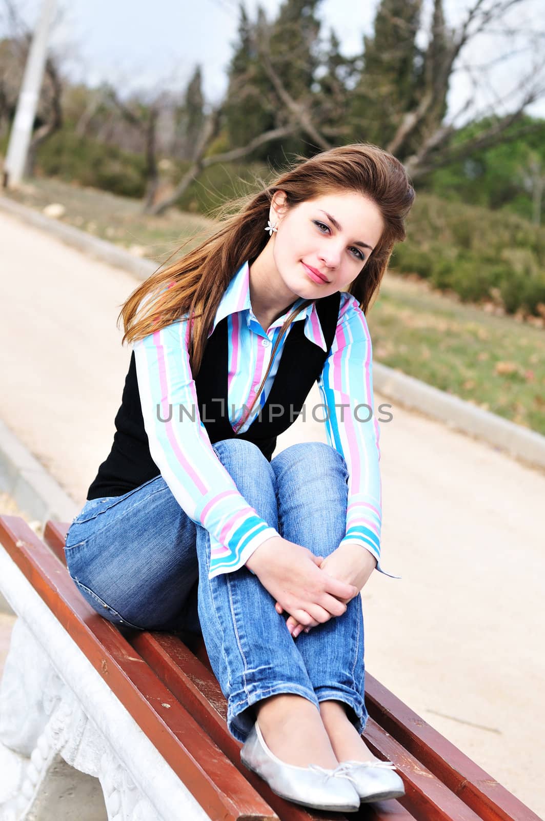   pretty teen girl resting in the park on the bench
