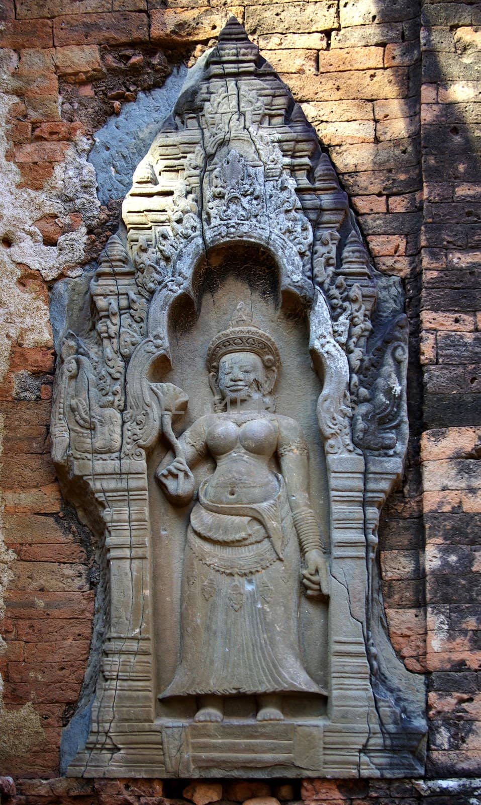 It's a view of one engraved women on a brik wall temple in Angkor