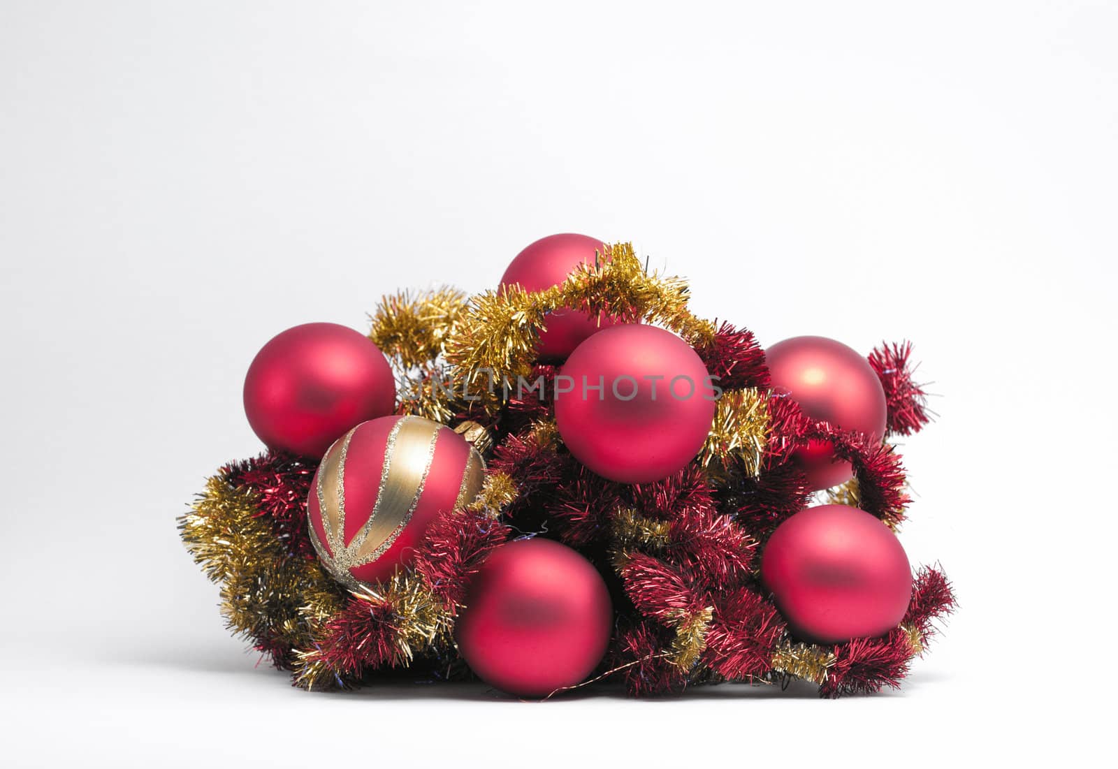 Christmas baubles on red & gold tinsel on a white background