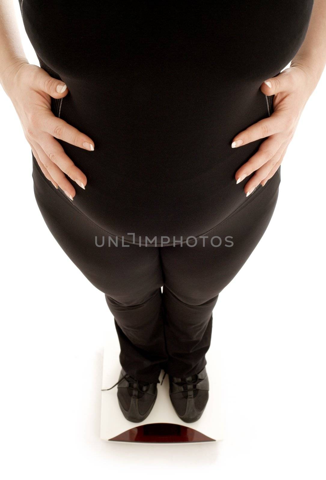 lovely pregnant lady weighing oneself over white background, focus on belly